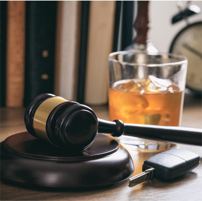 Gavel, keys, and an alcoholic drink on a desk